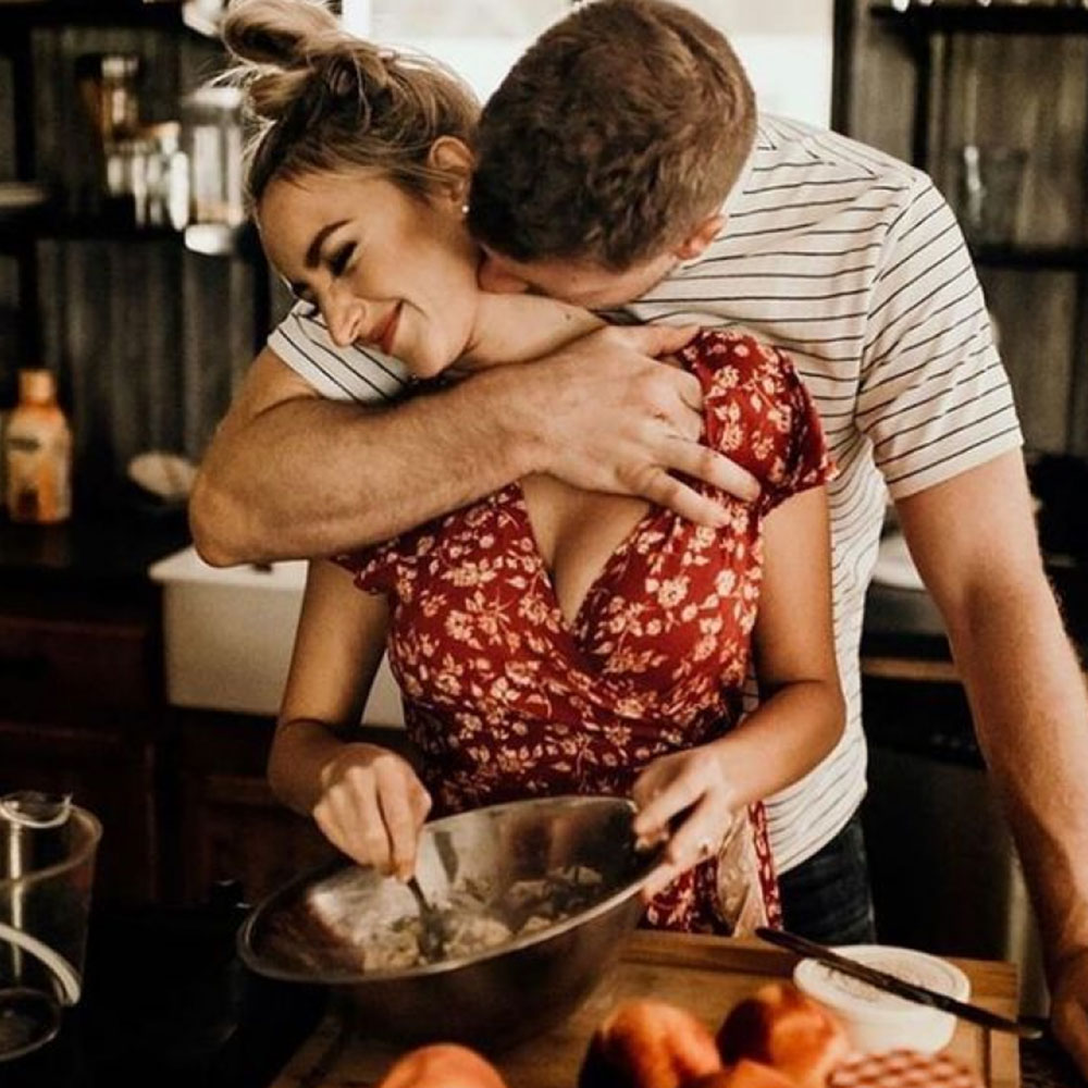 Man-kissing-girl-in-her-neck-while-she-bakes